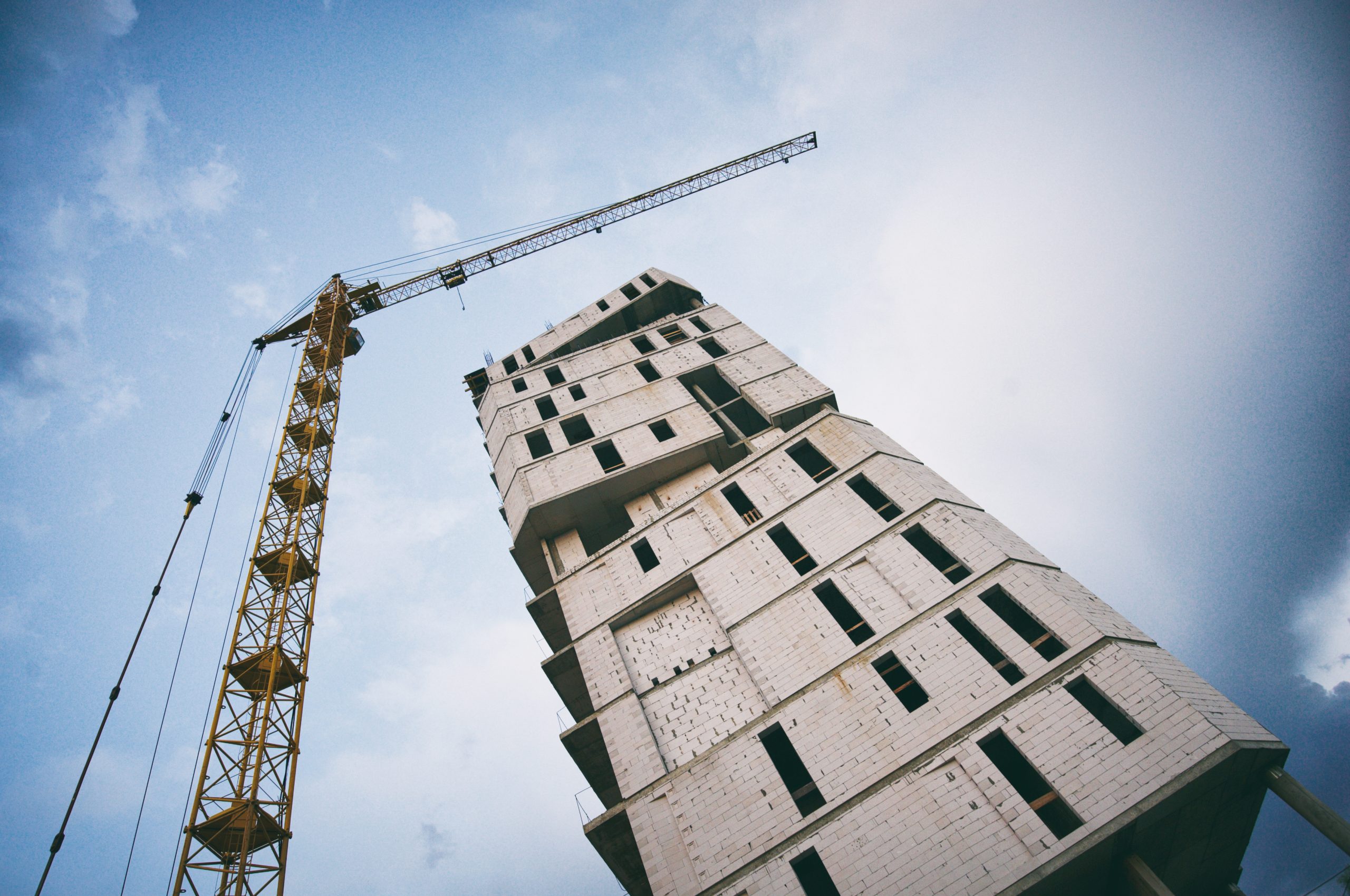 building of a skyscraper by cranes against cloudy sky