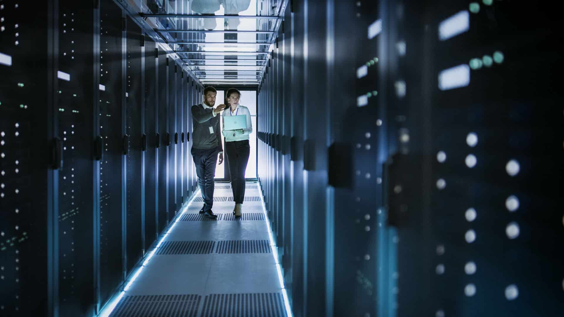 Two people walking between computer servers