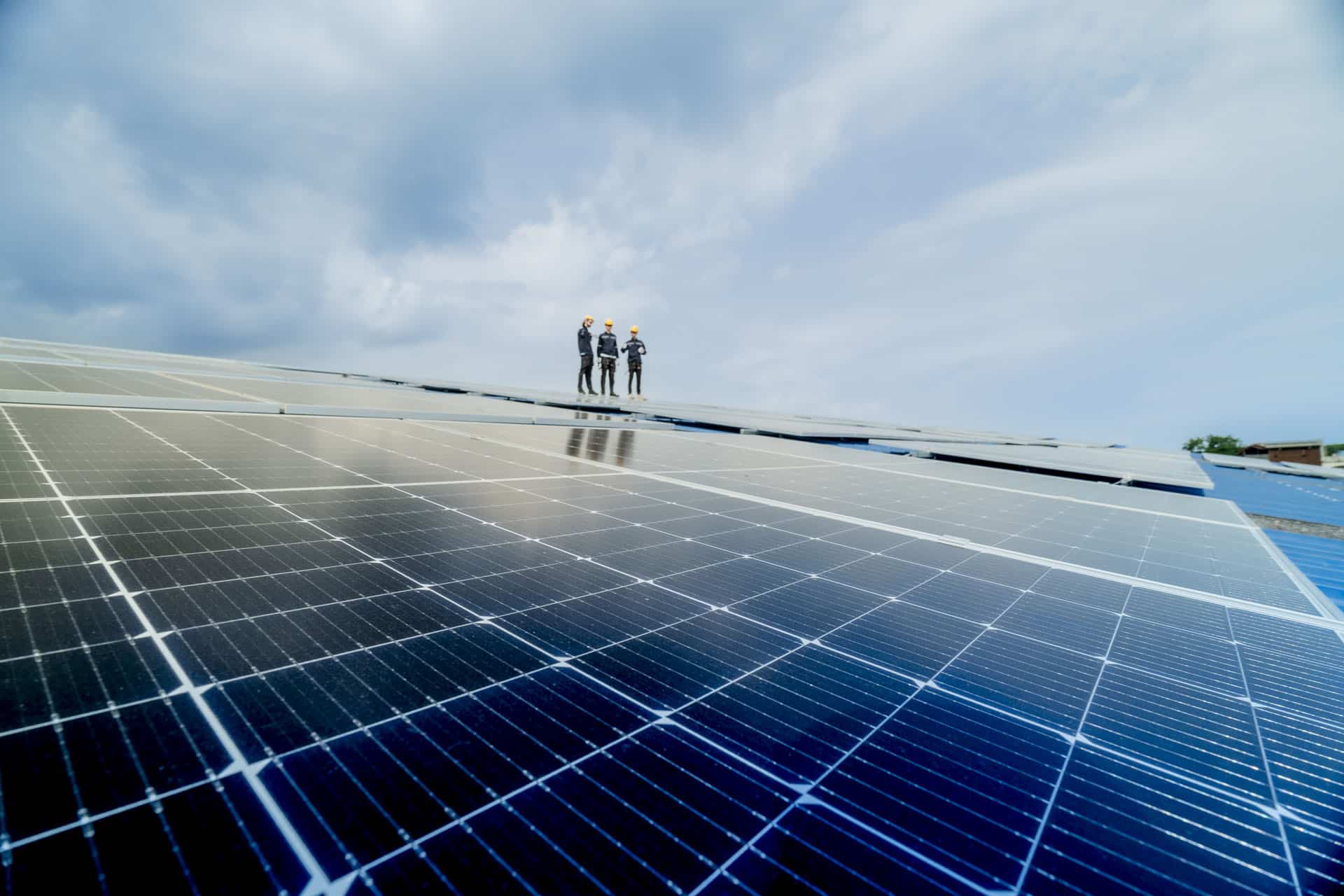 Three people in PPE looking at solar panel installation
