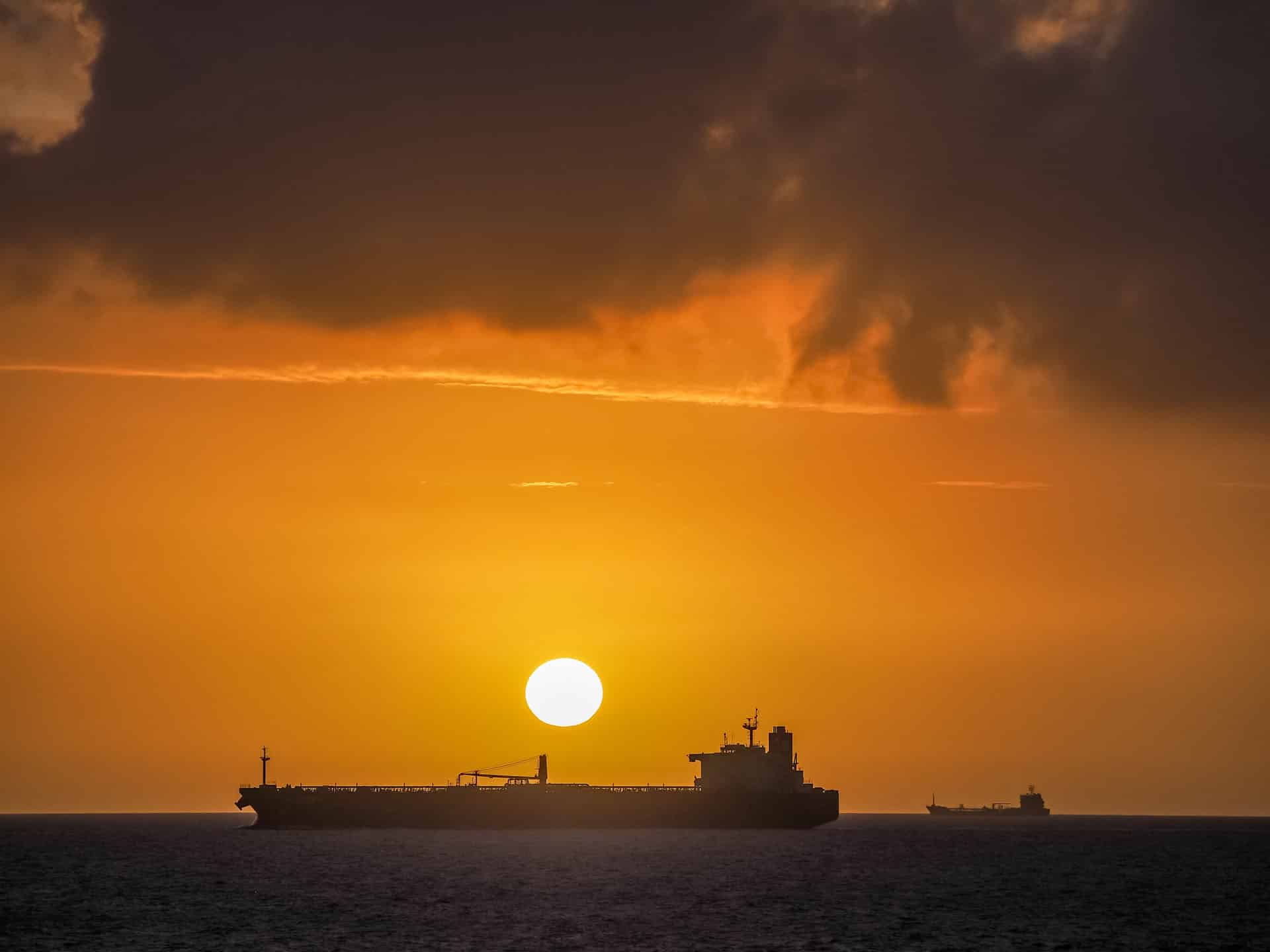 Sunsetting over silhouetted oil tanker at sea