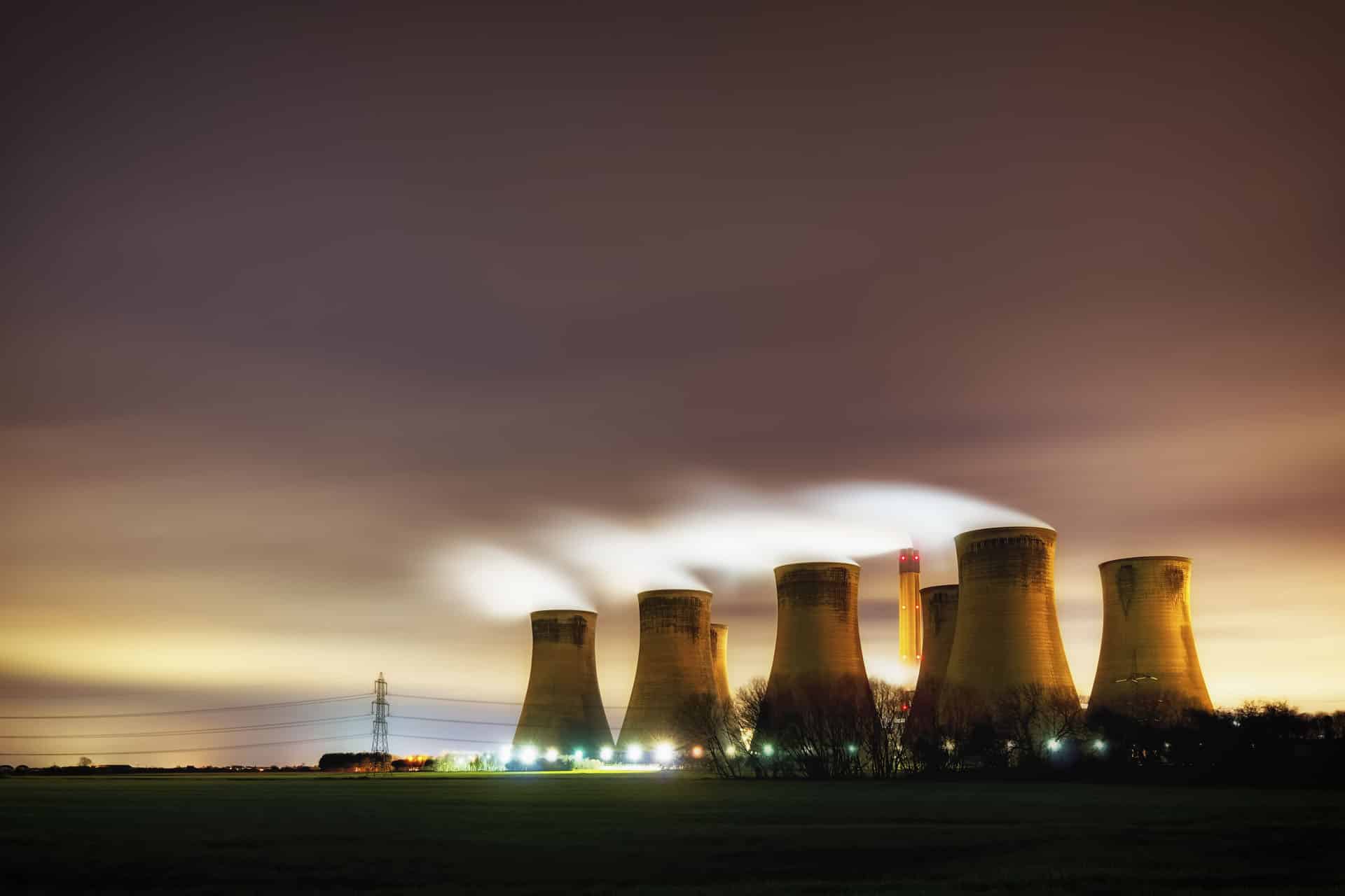 Multiple cooling towers producing steam in the evening